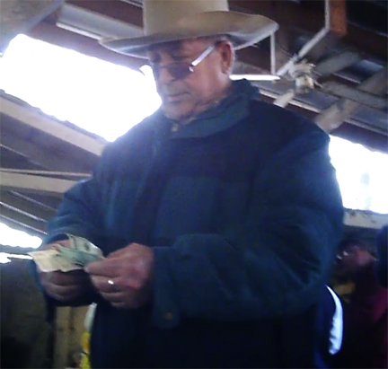 Braulio Hernandez counting cash from sale of pigs
